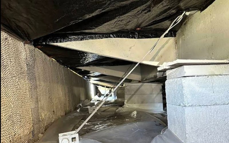 Steel tie-down straps anchored from the home’s floor joists to concrete piers in a crawl space, reinforcing structural stability and protecting against wind uplift — part of East Coast Vapor Barrier’s hurricane-hardening services.