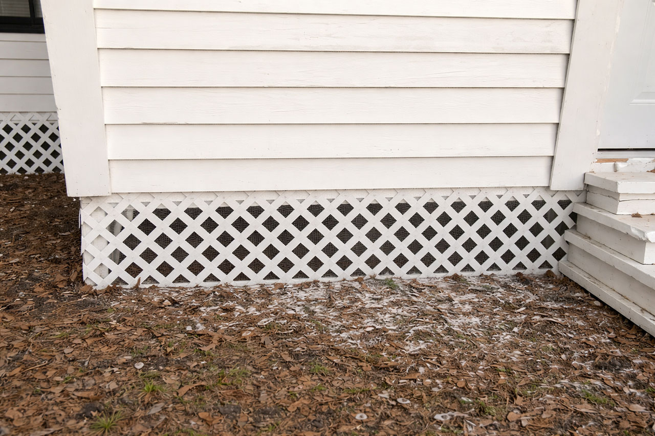 Vented lattice skirting along the base of a manufactured home, with corrosion-resistant mesh visible behind the openings.