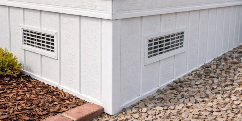 Clean, white vinyl skirting installed along the perimeter of a home’s foundation, featuring built-in ventilation grilles to promote airflow while protecting the crawl space from pests and weather.