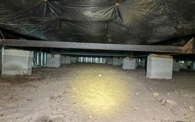 Open view of an unencapsulated crawl space with dirt floor, steel I-beams, and concrete piers — ready for East Coast Vapor Barrier’s full encapsulation service to improve air quality, energy efficiency, and structural longevity.